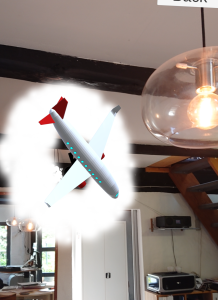 Screenshot fra AR-illustrationen af “iterativt design”, med faserne for idéudvikling, afprøvning, evaluering og justering: En papirflyver skydes ind i app-brugerens omgivelser, gennemgår flere transformationer og bliver til sidst til en flyvemaskine.